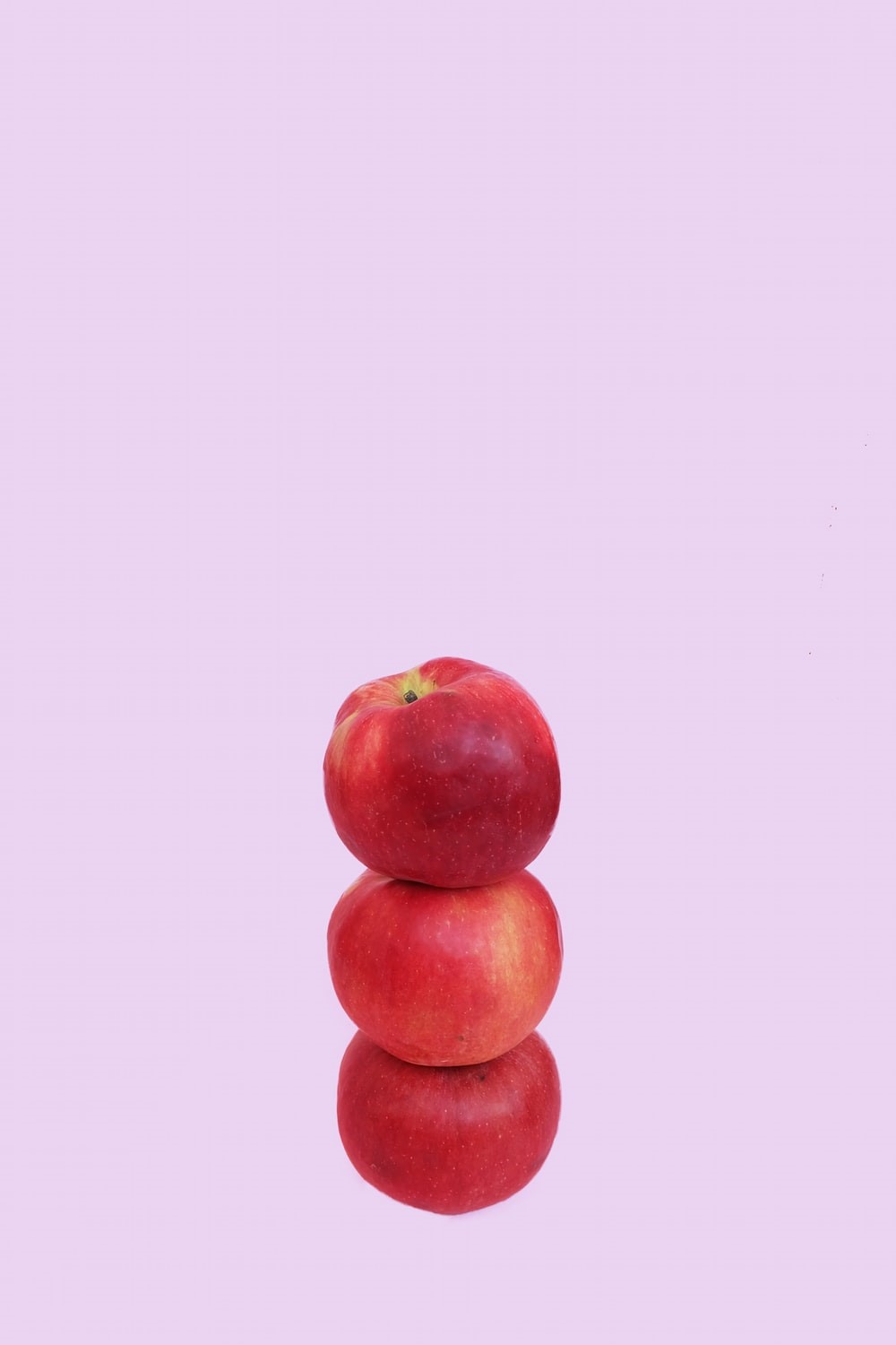 Stapel von zwei roten Äpfeln vor rosa Hintergrund. Aussage: Employer Brand Manager sind Balancehalter der Extraklasse.