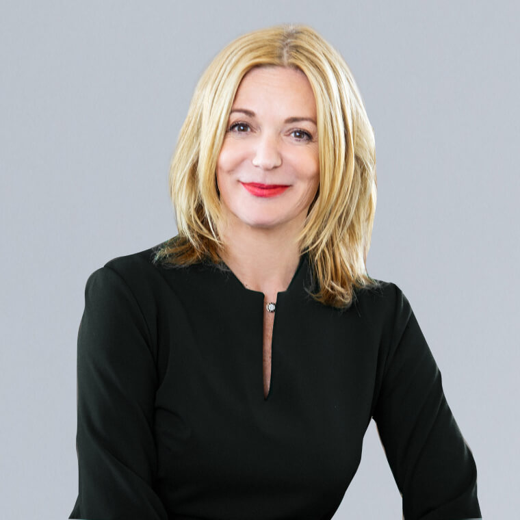 Portraitfoto einer blonden Frau mit rotem Lippenstift und mit einer schwarzen Bluse gekleidet. Zu sehen ist: Christiane Barho, Associated Consultant DEBA.