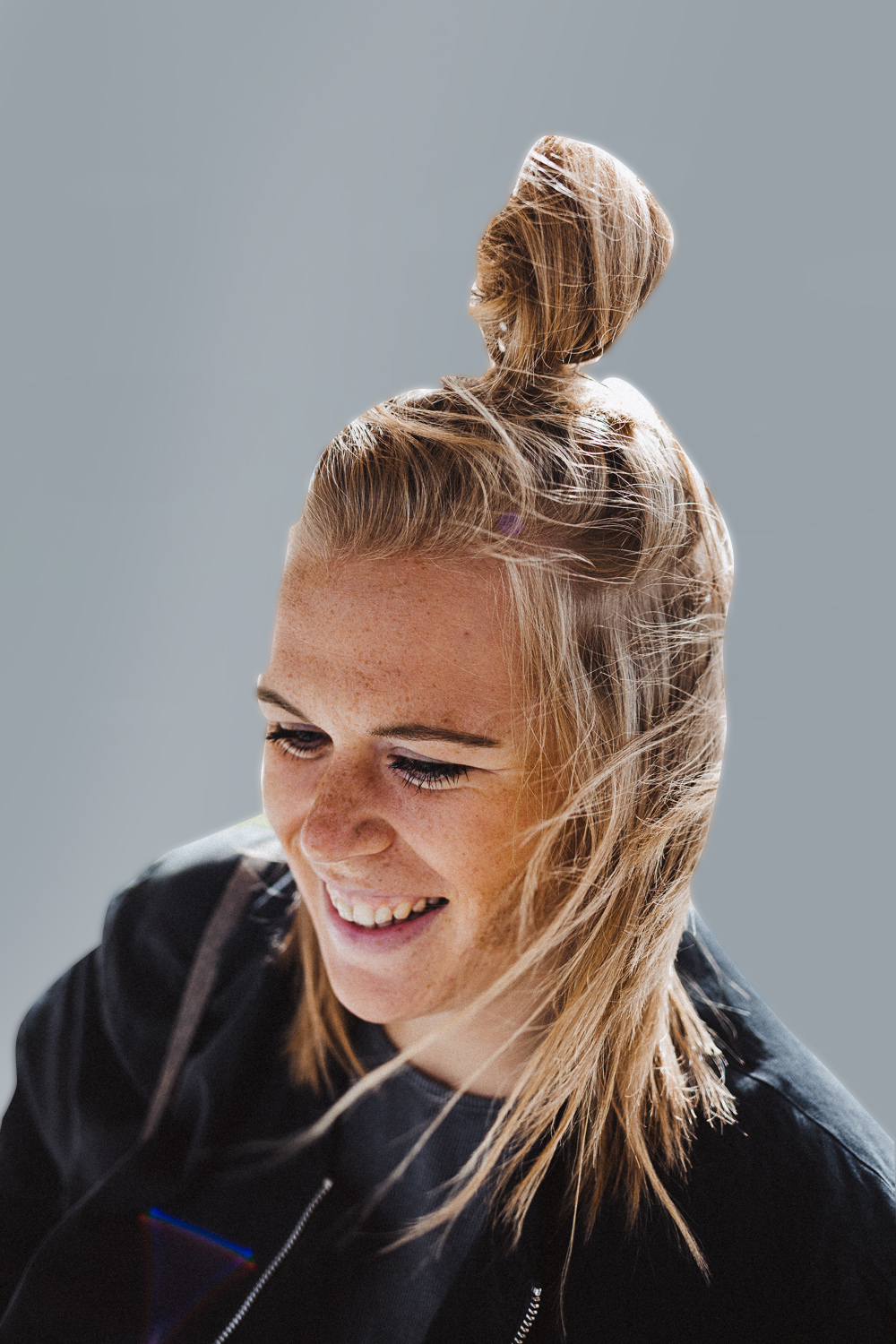 Foto einer lachenden, jungen Blondine im Profil vor grauem Hintergrund. Dabei handelt es sich um Sophie Böck, Projektassistentin der DEBA in Österreich.