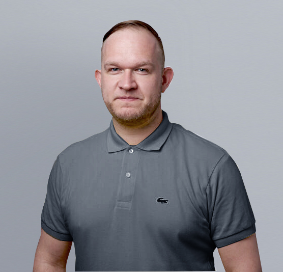 Professionelle Aufnahme eines Mannes in anthrazitfarbenem Poloshirt vor grauem Hintergrund. Dabei handelt es sich um MArcus Merheim, Director Growth & Marketing DEBA.